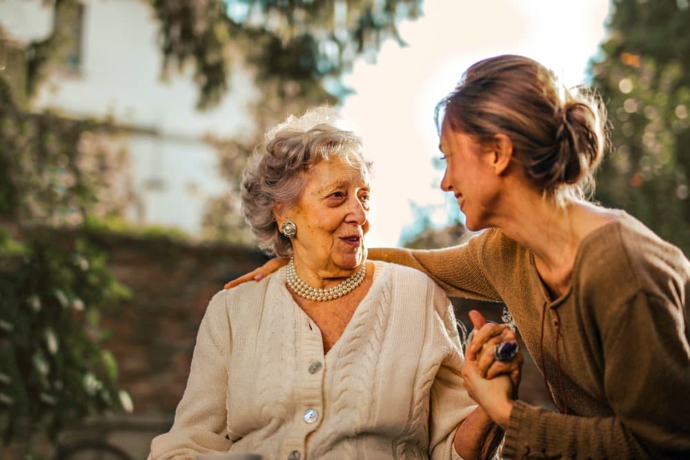 Une femme serrant les épaules de sa mère.