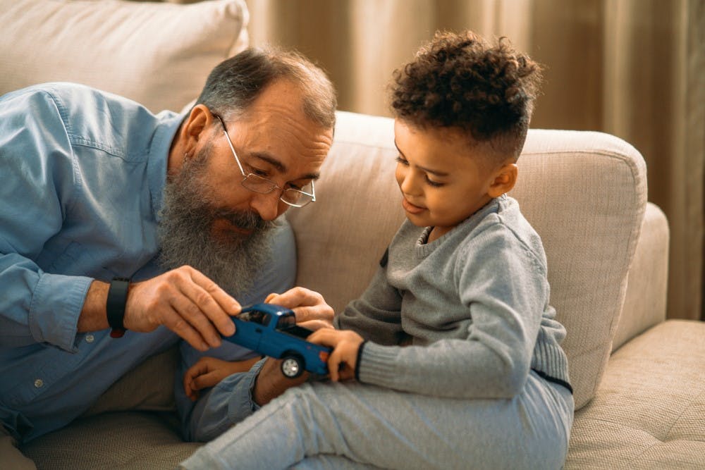 A father holding a toy vehicle with his son.