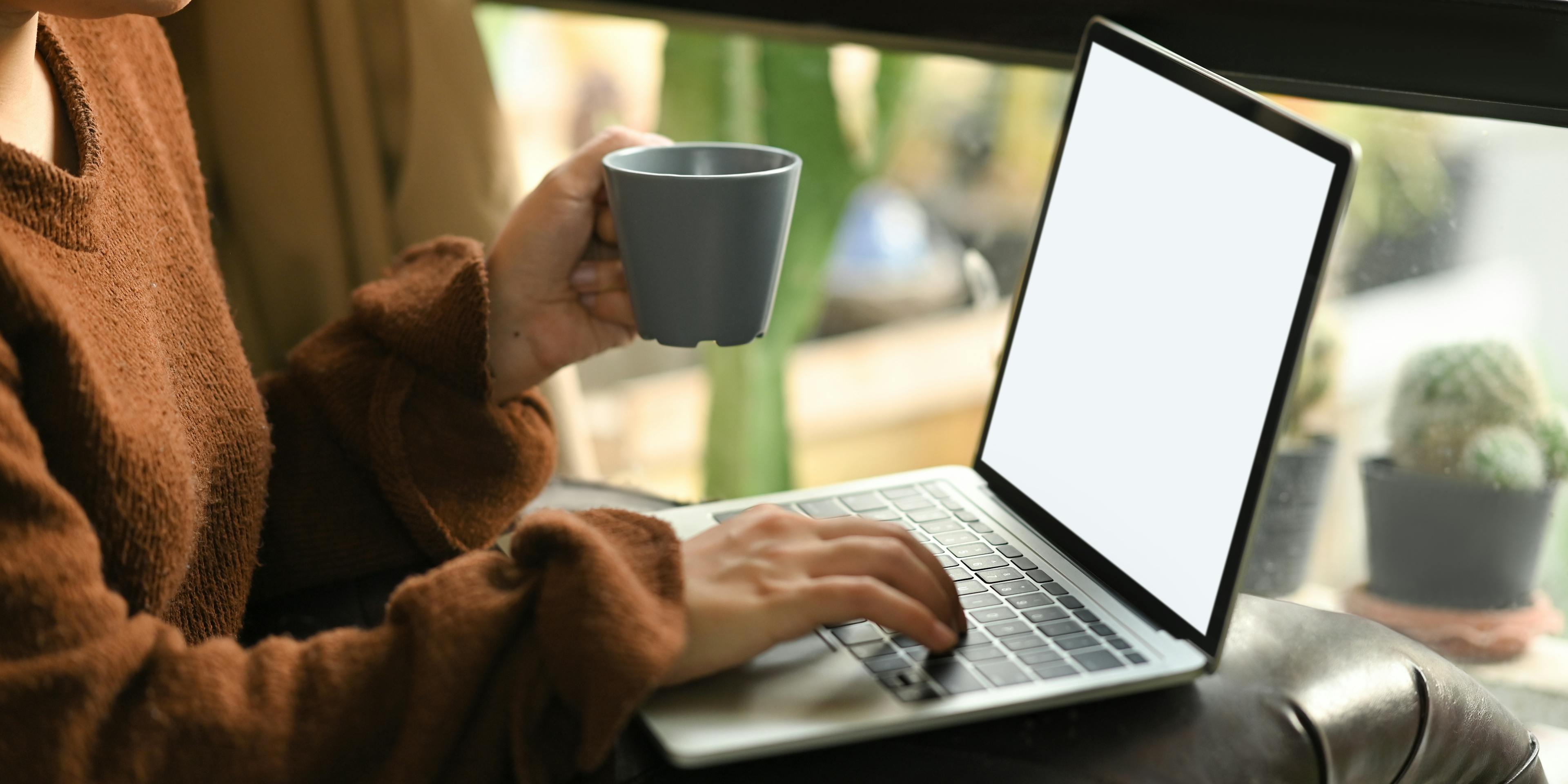 Une femme prenant son café tout en regardant son ordinateur portable